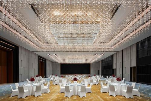 a banquet hall with white tables and chairs and a chandelier at Sheraton Guangzhou Panyu in Guangzhou