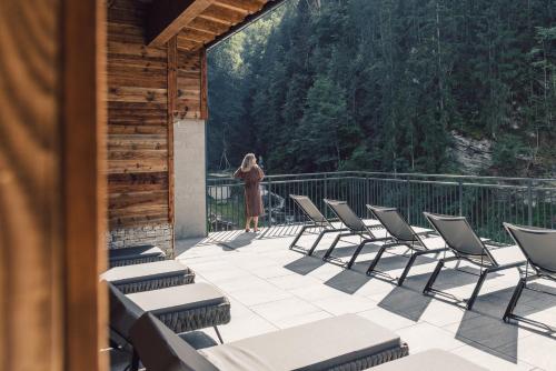 a woman is standing on a deck with chairs at Hotel - Gasthof Märzenklamm in Stumm