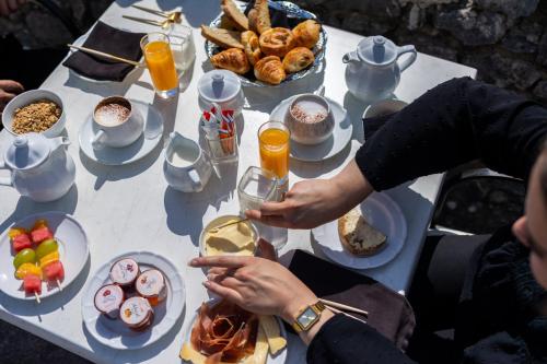 a table with food and drinks and a person holding a wine glass at Château de Trigance in Trigance