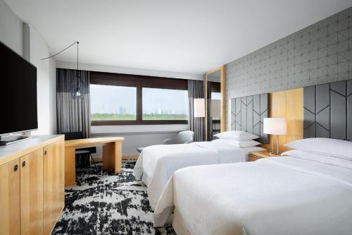 a hotel room with two beds and a flat screen tv at Sheraton Frankfurt Airport Hotel & Conference Center in Frankfurt/Main