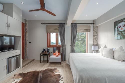 a bedroom with a bed and a flat screen tv at Baan Phu Prana Boutique Villa in Surin Beach