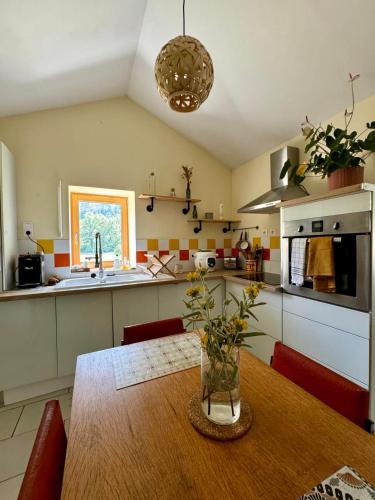 une cuisine avec une table en bois et un vase. dans l'établissement Au Rocher Troué, à Millau