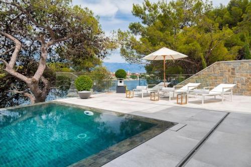 a swimming pool with chairs and an umbrella at Luxury Seafront Villa Prestige Brac with private pool, sauna and gym and private sea deck at the beach on Brac island in Selca