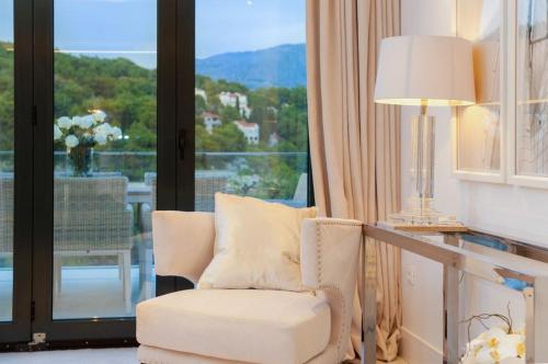 a white chair and a lamp in a room with a window at Luxury Seafront Villa Prestige Brac with private pool, sauna and gym and private sea deck at the beach on Brac island in Selca