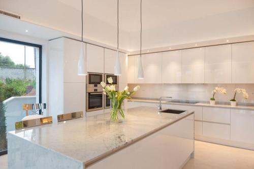 a white kitchen with a vase of flowers on a counter at Luxury Seafront Villa Prestige Brac with private pool, sauna and gym and private sea deck at the beach on Brac island in Selca