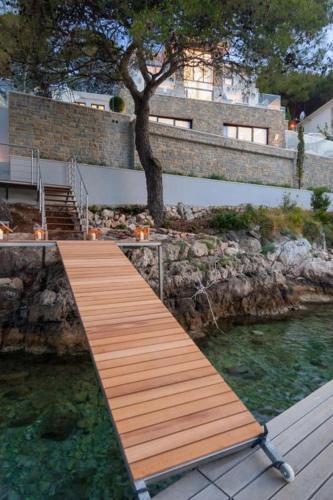 a wooden bridge over a body of water at Luxury Seafront Villa Prestige Brac with private pool, sauna and gym and private sea deck at the beach on Brac island in Selca