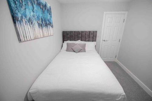a bedroom with a white bed with a painting on the wall at Beautiful, Peaceful, 5 Bedroom home with Hot Tub! in Manchester