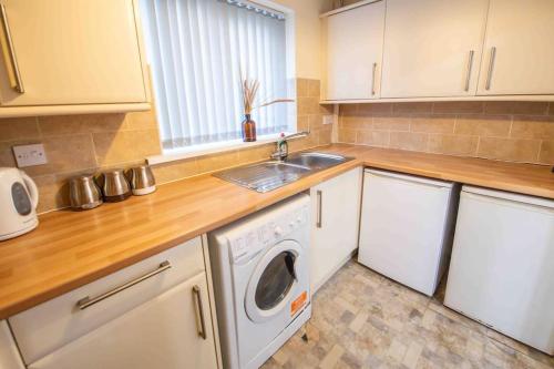 a kitchen with a sink and a washing machine at Beautiful, Peaceful, 5 Bedroom home with Hot Tub! in Manchester