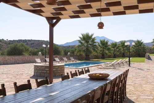 a wooden table with chairs and a swimming pool at Nestor Villa, with Heated Pool & Absolute Privacy in Roumelí