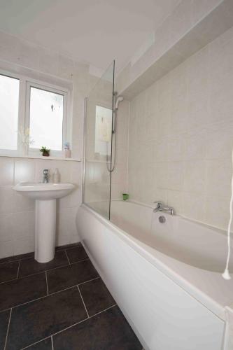 a white bathroom with a tub and a sink at Beautiful, Peaceful, 5 Bedroom home with Hot Tub! in Manchester