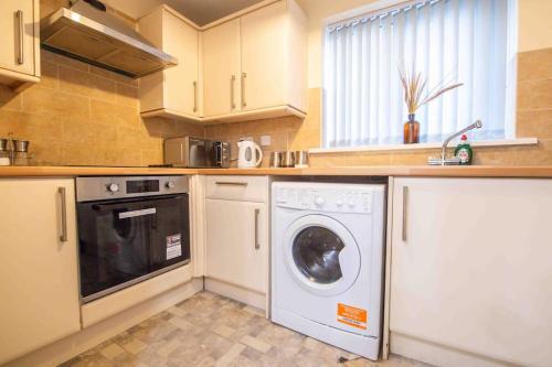 a kitchen with a washing machine and a sink at Beautiful, Peaceful, 5 Bedroom home with Hot Tub! in Manchester