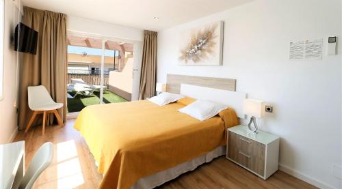a bedroom with a large bed with a yellow blanket at Hotel Gabarda in Palmanova