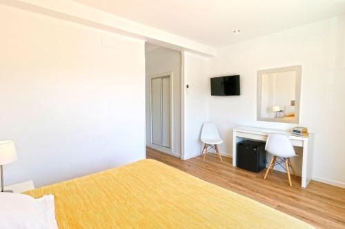 a bedroom with a bed and a desk with two chairs at Hotel Gabarda in Palmanova
