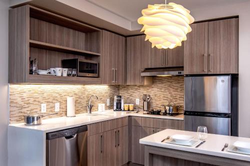 a kitchen with wooden cabinets and a chandelier at Element Hampton Peninsula Town Center in Hampton