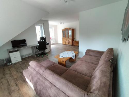 a living room with a brown couch and a table at Ferienwohnung Karin 65355 in Moormerland