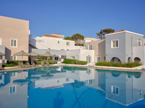 a swimming pool in a villa with white buildings at Atlantica Marmari Palace in Mastichari