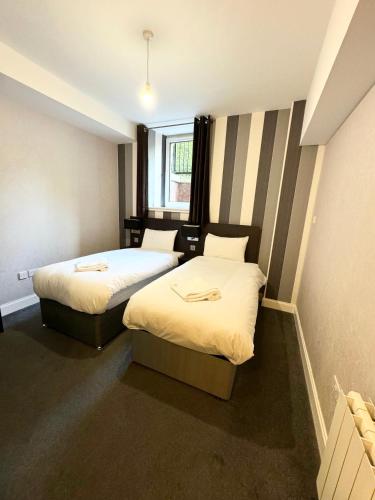 two beds in a small room with a window at Murrayfield Park Guest House in Edinburgh