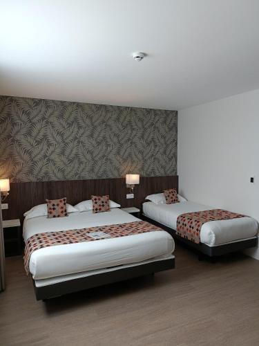 a hotel room with two beds and a wall at Brit Hotel Ploermel - Hotel de l'Hippodrome in Ploërmel