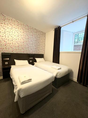 two beds in a small room with a window at Murrayfield Park Guest House in Edinburgh