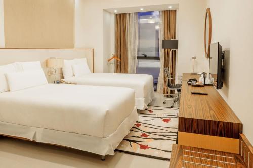 a hotel room with two beds and a television at Element by Westin Hotel Dar es Salaam in Dar es Salaam