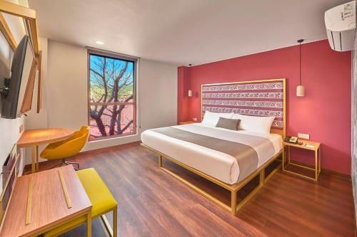 オアハカにあるCity Centro by Marriott Oaxacaの赤い壁のベッドルーム1室(大型ベッド1台付)