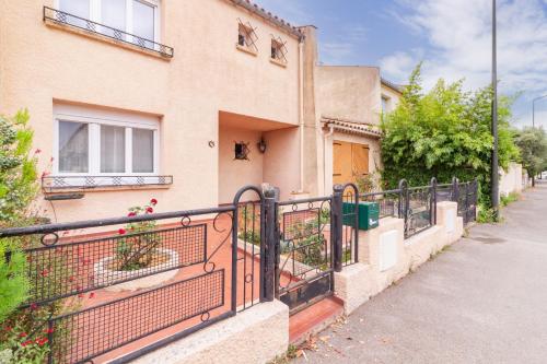 une maison avec une clôture noire devant elle dans l'établissement La Douce Occitane - Maison climatisée pour 6, à Carcassonne