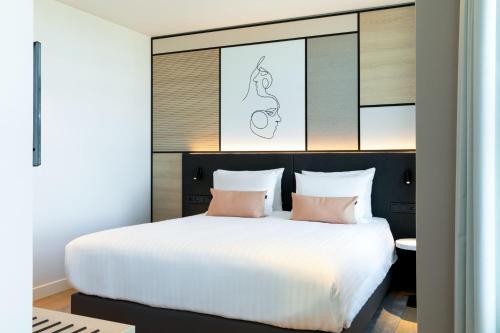 a bedroom with a large white bed with pink pillows at Residence Inn by Marriott The Hague in The Hague