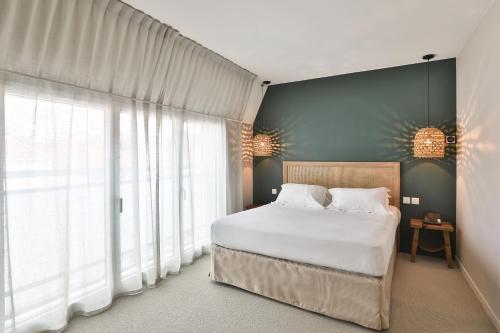 a bedroom with a bed and a large window at Hotel & Spa Les Roches Noires in Les Sables-dʼOlonne