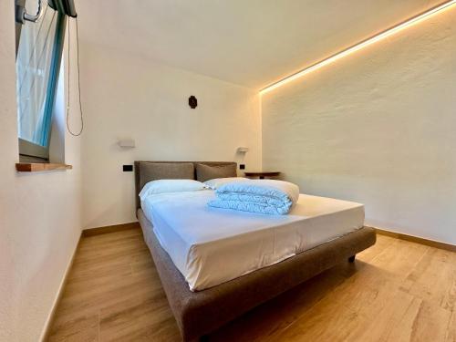 a bedroom with a bed with white sheets and blue pillows at Maison Rosset agriturismo, camere, APPARTAMENTI e spa in Valle d'Aosta in Nus