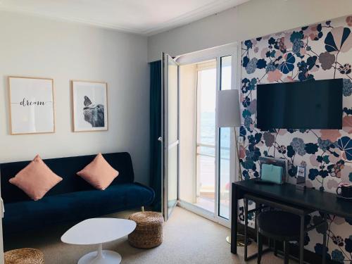 a living room with a blue couch and a table at Hotel & Spa Les Roches Noires in Les Sables-dʼOlonne