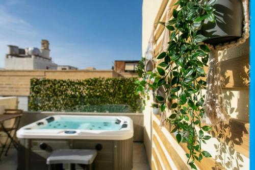 a hot tub on a balcony with a plant at Mandera's Boutique Suites & Dorms in Valletta