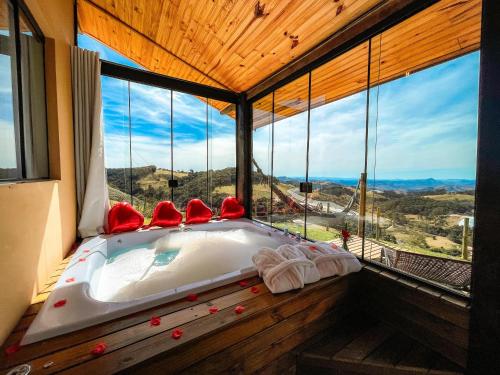 a bath tub in a room with a large window at Chalé Vista do Paraíso in Gonçalves
