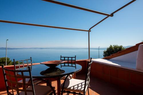 a table and chairs on a balcony with a view of the ocean at Porto Santo Stefano - Unique Maison in Porto Santo Stefano