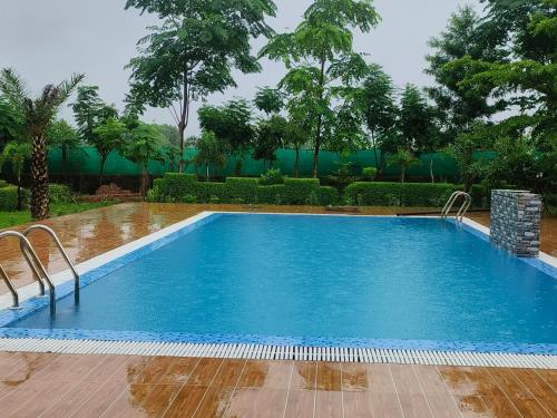 a large swimming pool in a yard with trees at Nature life farm in Chonp