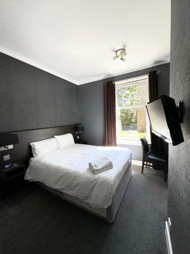 a bedroom with a white bed and a television at Murrayfield Park Guest House in Edinburgh