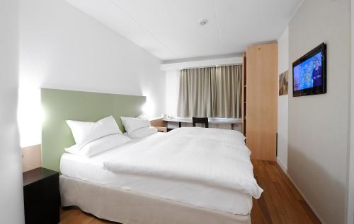 una camera da letto con un letto bianco e una televisione di Good Morning Kista a Stoccolma
