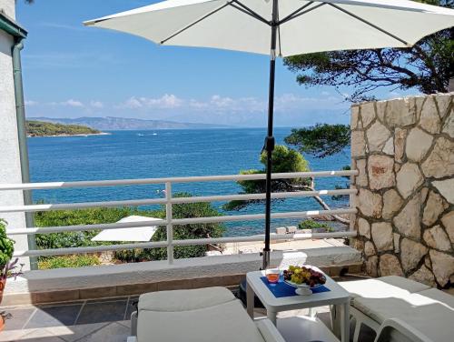 a patio with a table and an umbrella and the ocean at Suite Hvar Park Beach Villa, Hvar Ana Nikola Villas in Jelsa