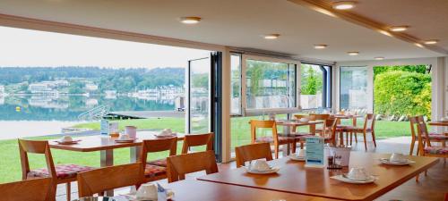 a restaurant with tables and chairs and a large window at Barry Memle Directly at the Lake in Velden am Wörthersee