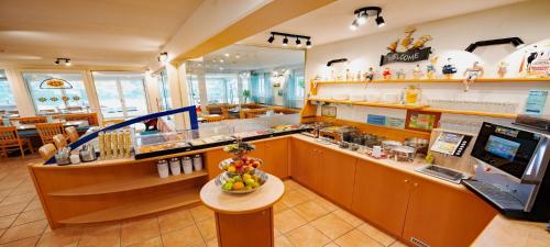 a restaurant with a counter with a bowl of fruit on a table at Barry Memle Directly at the Lake in Velden am Wörthersee