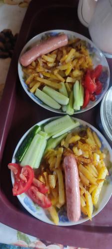 twee borden met eten, inclusief een hotdog en friet bij Elai Guest House in Kazarman
