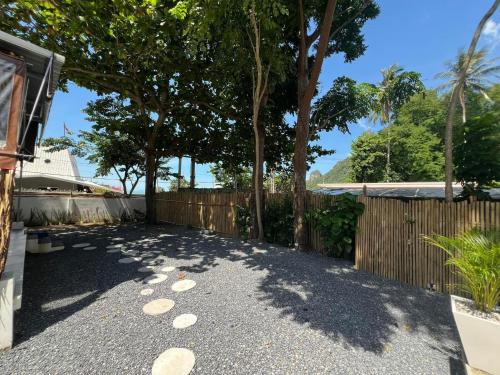 a driveway with a fence and trees in a yard at Chill Lay Resort Donsak in Don Sak