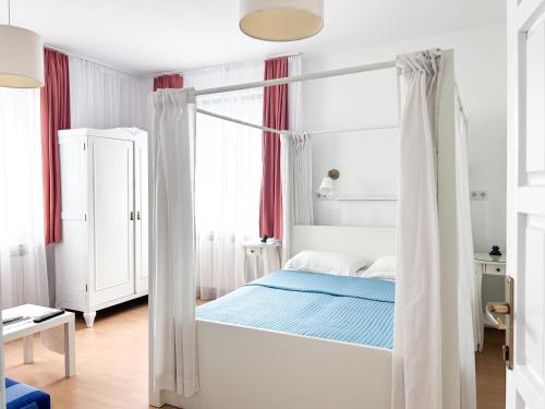 ein weißes Schlafzimmer mit einem Himmelbett mit blauer Bettwäsche in der Unterkunft Apartments Diva in Sarajevo