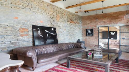 a leather couch in a living room with a brick wall at Vigne di Fagnano 1709 Eco Relais in Santo Stefano Belbo