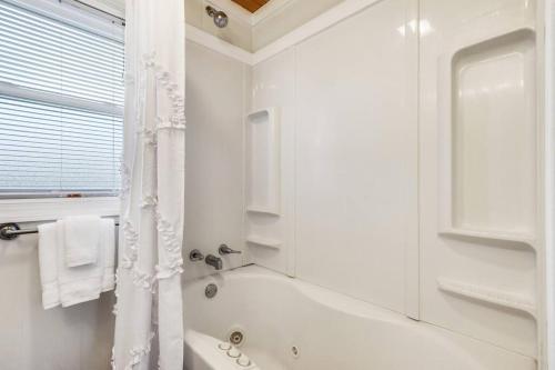 un bagno bianco con vasca e doccia di Cozy cottage by the Sea -near downtown with patio! a Gulfport