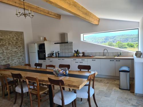 une cuisine avec une table en bois et une grande fenêtre dans l'établissement Le Madrès, à Joch