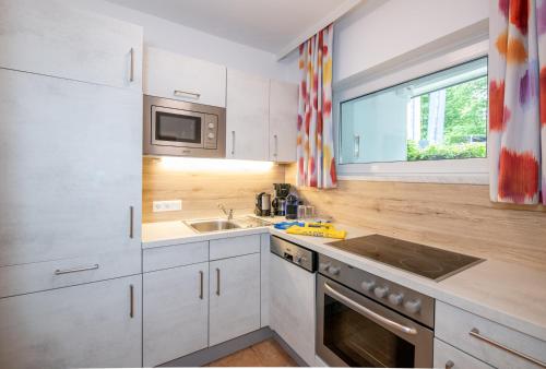 a kitchen with white cabinets and a sink and a window at Barry Memle Directly at the Lake in Velden am Wörthersee
