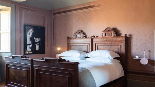 a bedroom with a large wooden bed with white pillows at Vigne di Fagnano 1709 Eco Relais in Santo Stefano Belbo