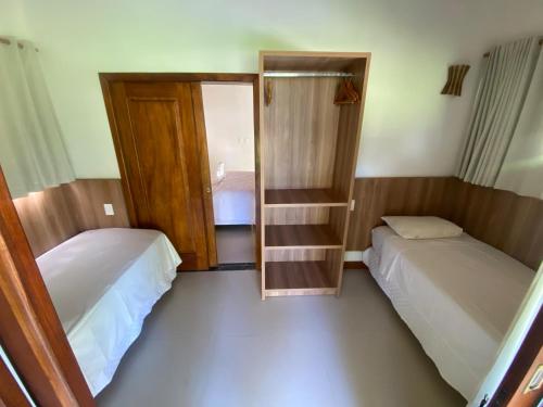 a small room with two beds and a mirror at Pousada Porto da Barra in Barra Grande