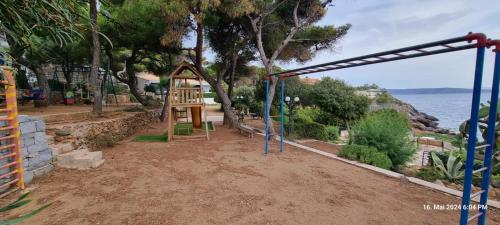 a playground with a swing set and the water at Poseidons Retreat optional el car and airporttrans in Sounio