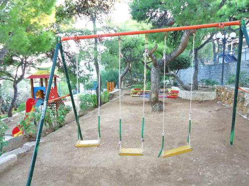 a swing set in a park with a playground at Poseidons Retreat optional el car and airporttrans in Sounio